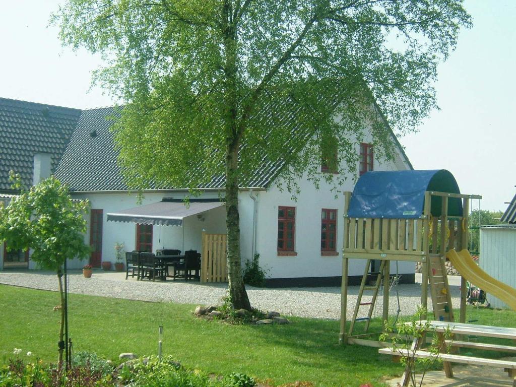 a playground in front of a house with a tree at Skjoldbjerg Garnihotel in Vorbasse