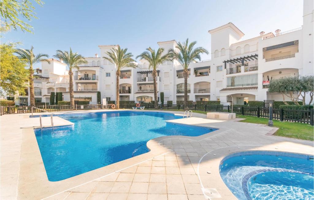 a swimming pool in front of a building with palm trees at 2 Bedroom Amazing Apartment In Roldán in Los Tomases