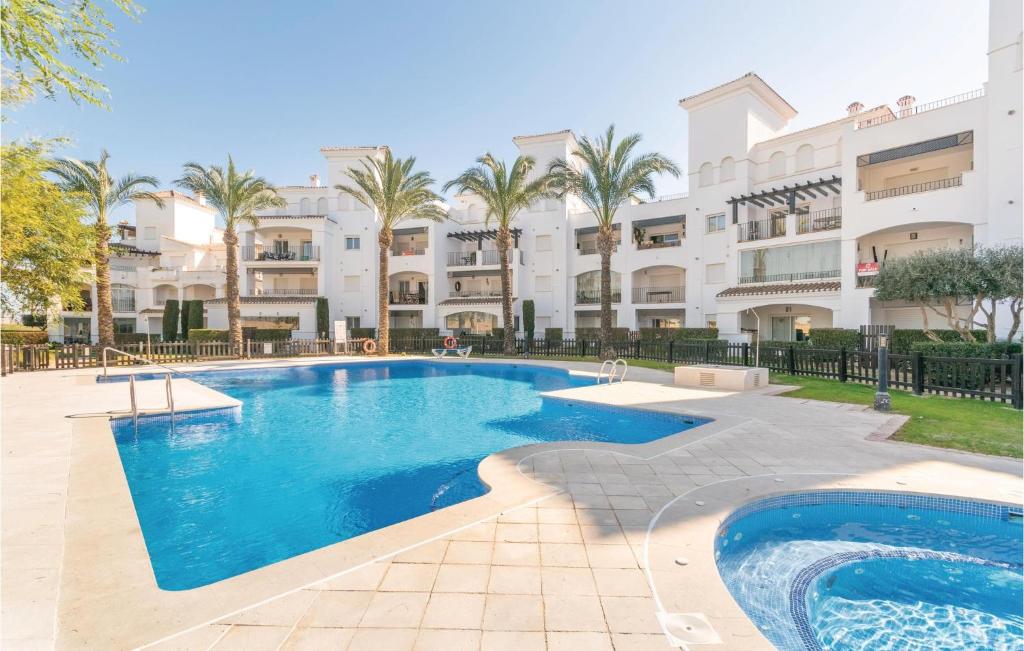 una piscina frente a un edificio con palmeras en Beautiful Apartment In Roldn With 2 Bedrooms, Wifi And Outdoor Swimming Pool, en Los Tomases