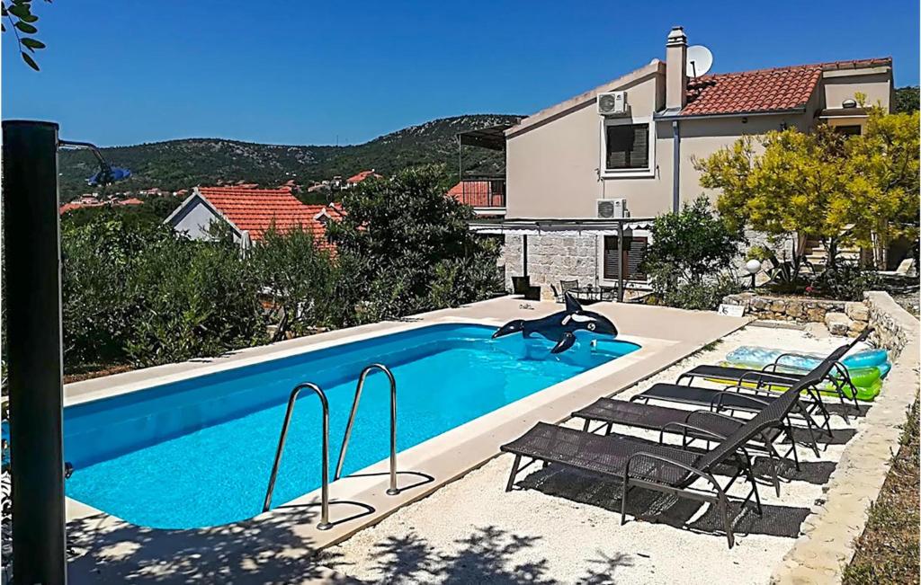 una piscina con 2 sillas y una casa en Awesome Home In Vinisce With Outdoor Swimming Pool en Vinišće