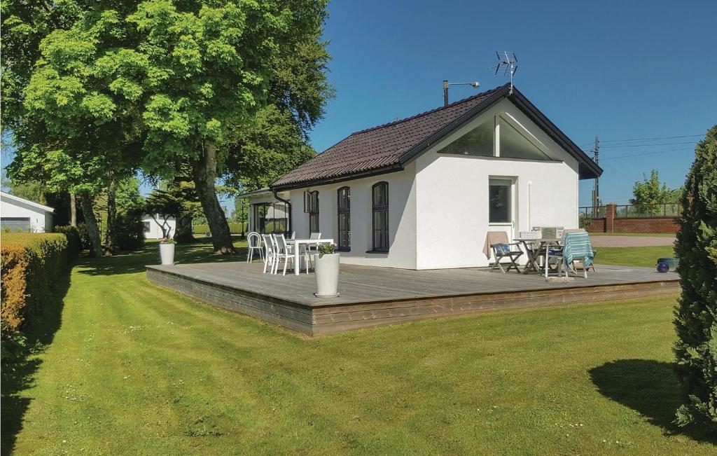 une petite maison blanche avec une terrasse dans une cour dans l'établissement Cozy Home In Svedala With Kitchen, à Svedala