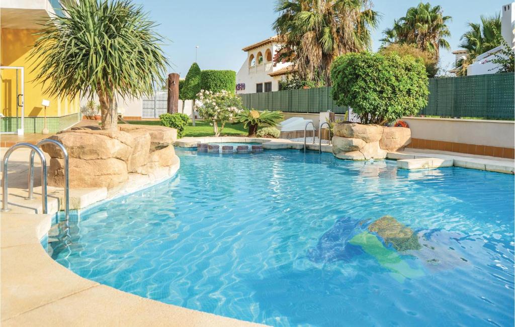 奧利維拉科斯塔的住宿－2 Bedroom Gorgeous Apartment In Orihuela Costa，一座大游泳池,位于一个树木繁茂的庭院内