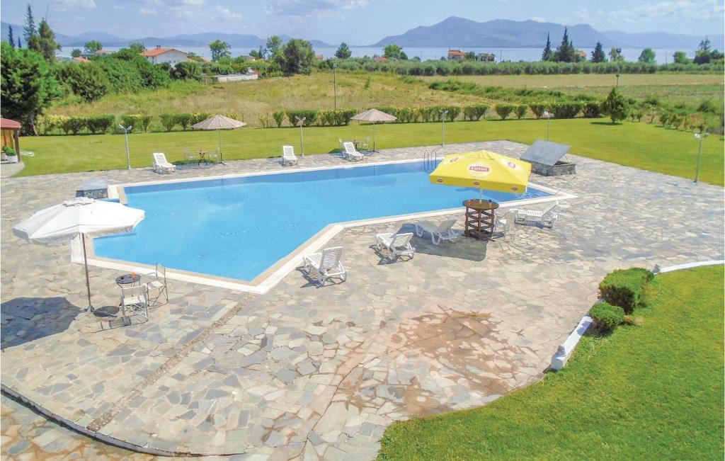 a swimming pool with a yellow umbrella and chairs at Gorgeous Home In Kamena Vourla With Outdoor Swimming Pool in Kamena Vourla
