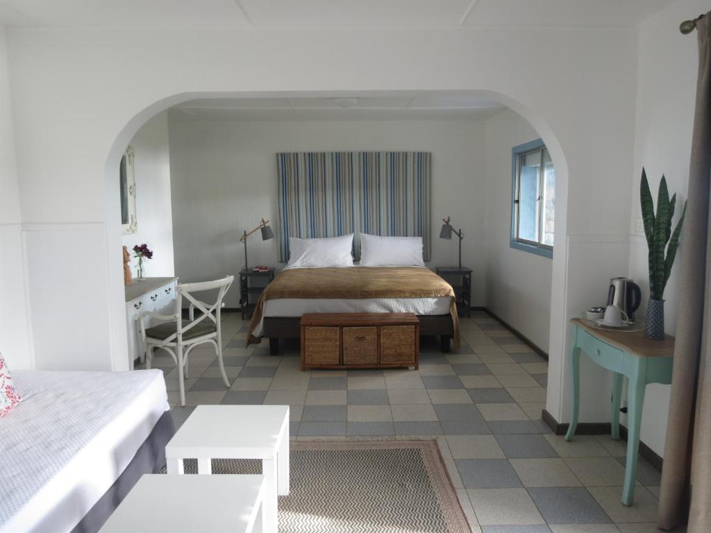 a bedroom with a bed and a table and a desk at Hotel Boutique La Perouse in Hanga Roa