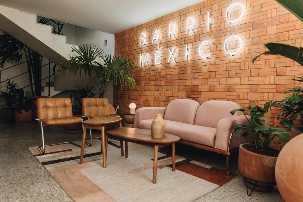 a lobby with a couch and chairs and a brick wall at Casa Ixaya by Barrio México in Guadalajara
