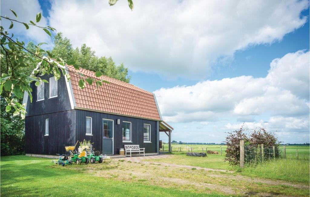 una casa negra con techo rojo en un campo en Farm Stay, en Schellinkhout