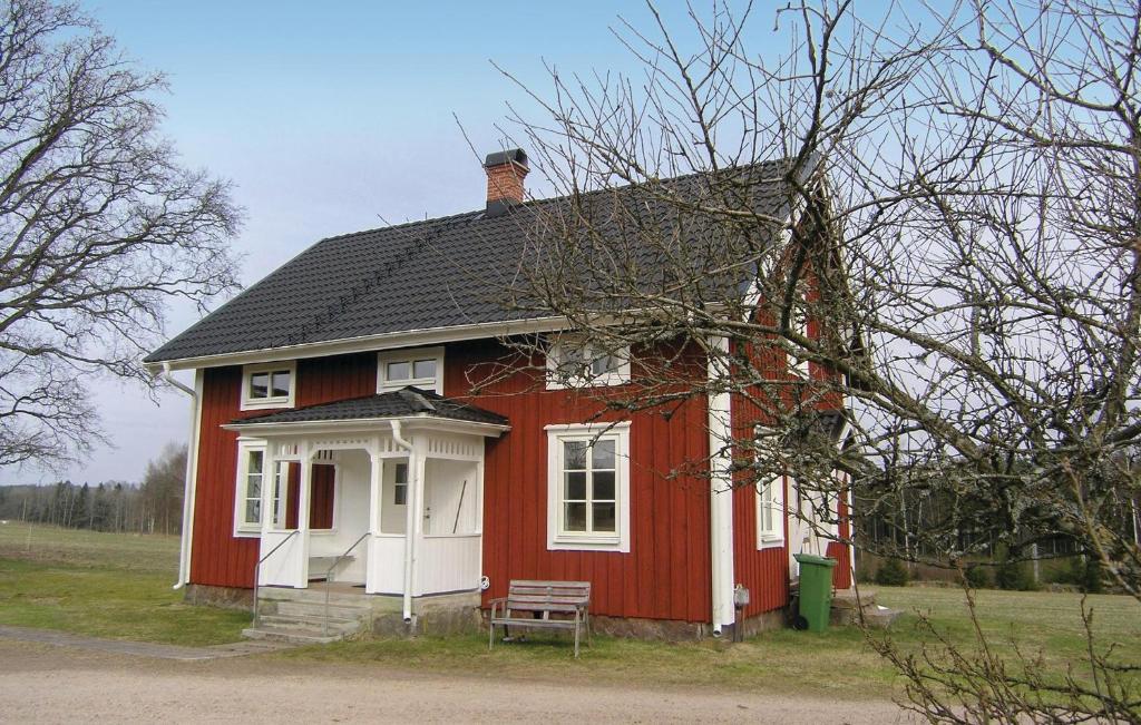 uma casa vermelha com um banco à frente em Cozy Home In Hestra With Kitchen em Valdshult