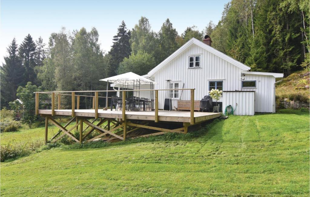a house with a large deck in the yard at 2 Bedroom Stunning Home In Strmstad in Lommeland