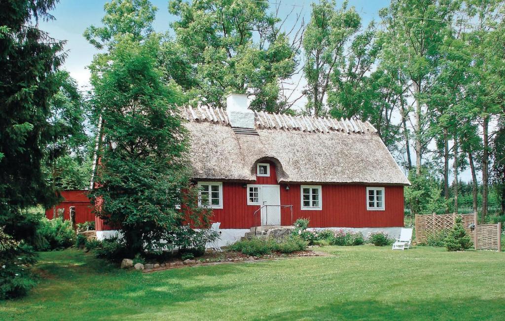 una casa roja con techo de paja en un patio en Stunning Home In Linderd With Wifi en Bösarp