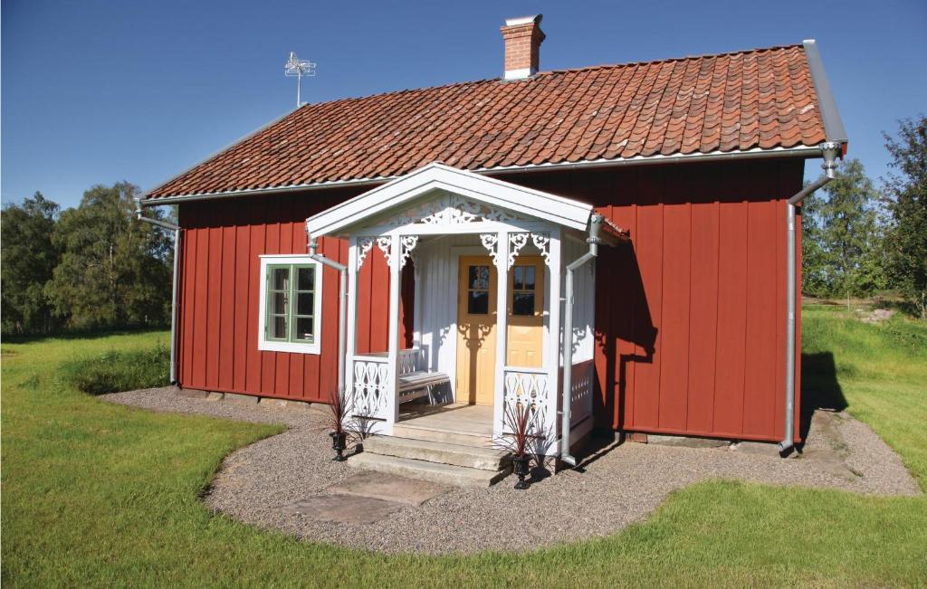 einen roten Schuppen mit einer weißen Tür und einer Veranda in der Unterkunft Lovely Home In Vaggeryd With Kitchen in Vaggeryd