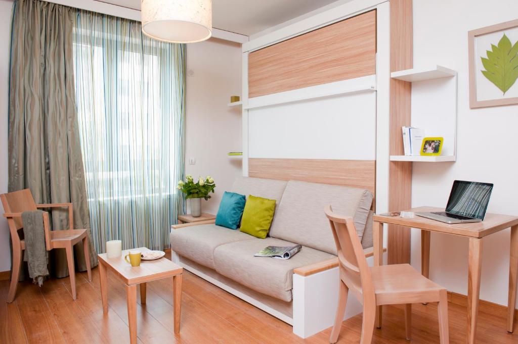 een woonkamer met een bank en een tafel met een laptop bij Aparthotel Adagio Paris Vincennes in Vincennes