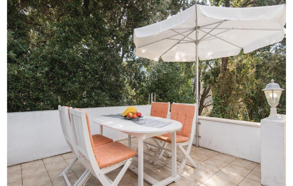 a white table and chairs with an umbrella at Cozy Apartment In Zuljana With Wifi in Žuljana