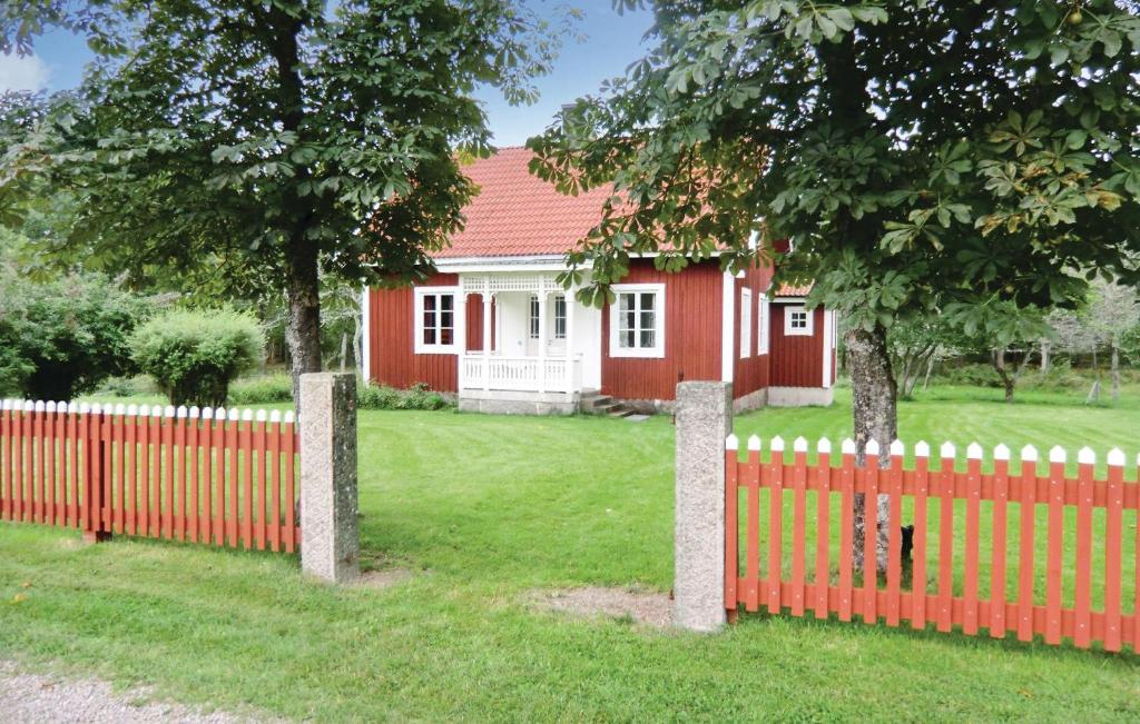 a red fence in front of a red and white house at Amazing Home In Blomstermla With 2 Bedrooms in Barnebo