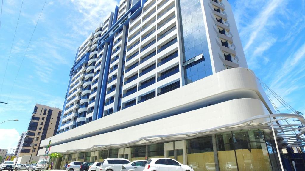 un grand bâtiment avec des voitures garées devant lui dans l'établissement Apartamento de alto luxo., à Maceió
