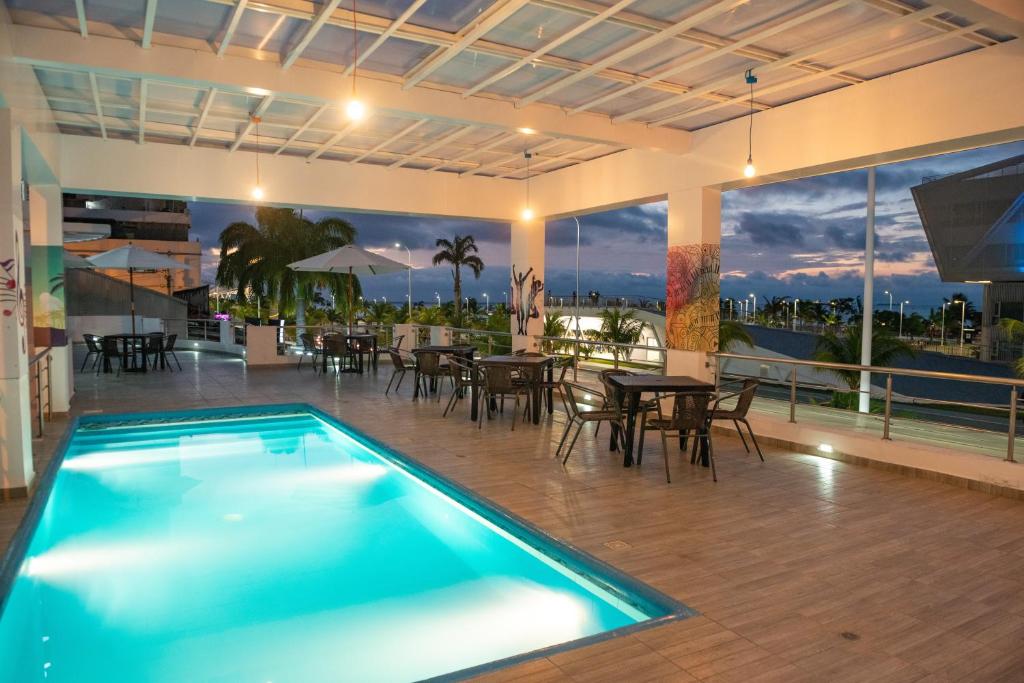 a swimming pool in a building with tables and chairs at Hotel Casa Arnaldo "Esmeraldas" in Esmeraldas