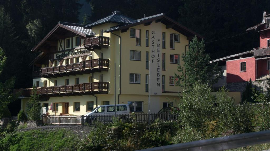 聖安東阿爾貝格的住宿－"Quality Hosts Arlberg" Hotel-Gasthof Freisleben，前面有停车位的建筑