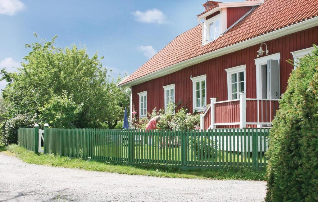 ein rotes Haus mit einem grünen Zaun in der Unterkunft Lovely Home In Eskilstuna With House Sea View in Sundby