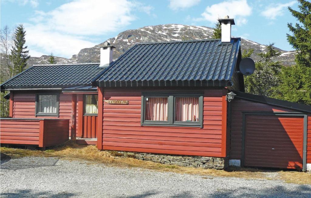 een rood en zwart huis met een berg op de achtergrond bij Petterbua in Kleivi
