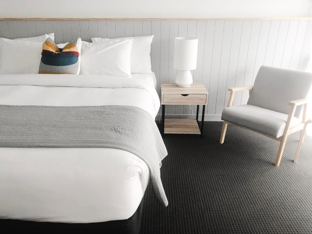 ein Schlafzimmer mit einem weißen Bett und einem Stuhl in der Unterkunft Eight Spence in Warrnambool