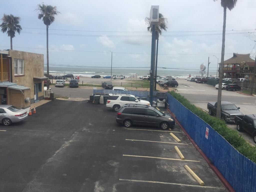 un estacionamiento con autos estacionados al lado del océano en Beachtree Motel en Galveston