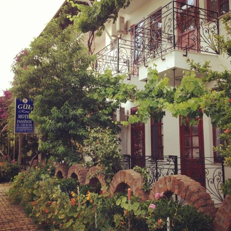 a white building with balconies and flowers in front of it at Rose Pension in Dalyan
