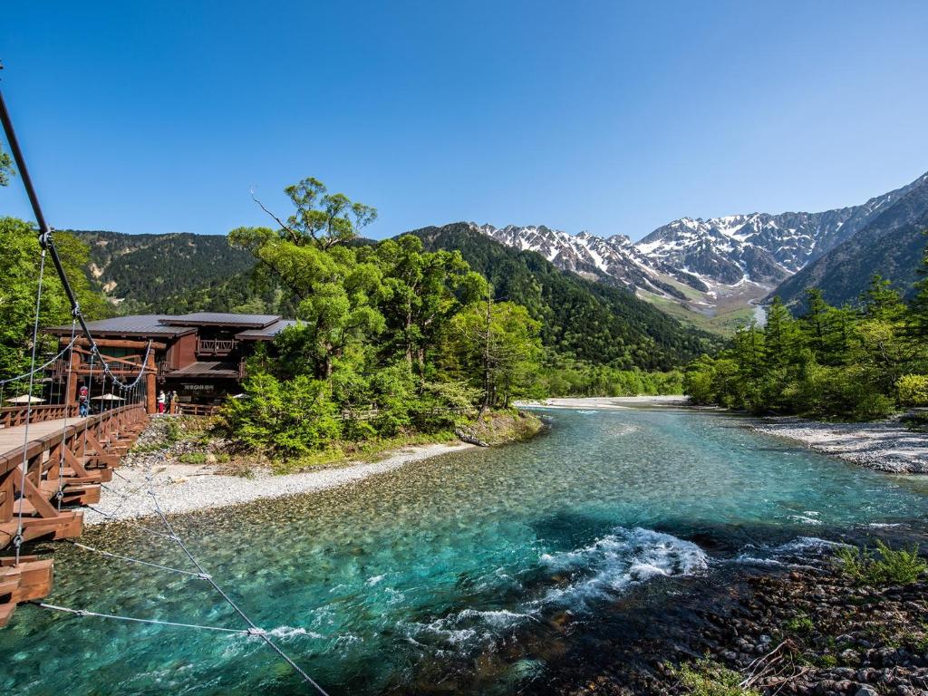 vistas a un río con montañas en el fondo en Kamikochi Hotel Shirakabaso en Matsumoto