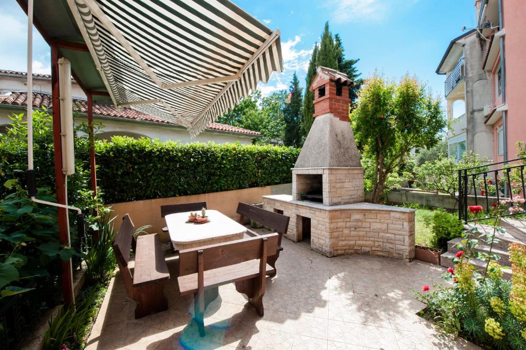 patio con mesa y chimenea de ladrillo en Apartments Vidaković en Rovinj