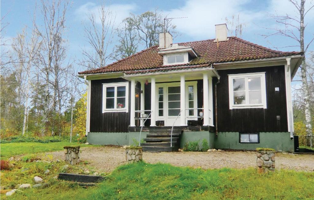 een klein zwart huis met een witte deur en ramen bij Lovely Home In Storebro With Kitchen in Storebro