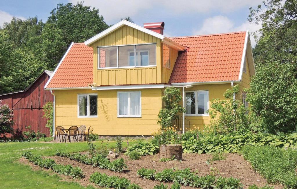 una casa amarilla con techo naranja y jardín en Nice Home In Vessigebro With Kitchen, en Vessigebro