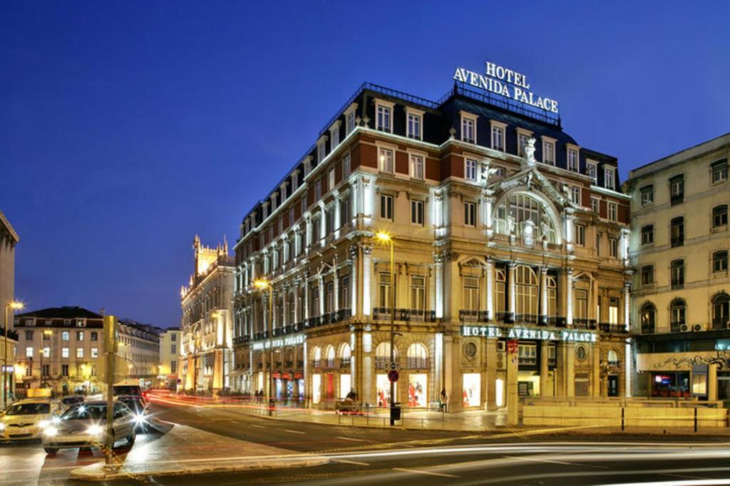 a building on the corner of a street at night at Hotel Avenida Palace in Lisbon