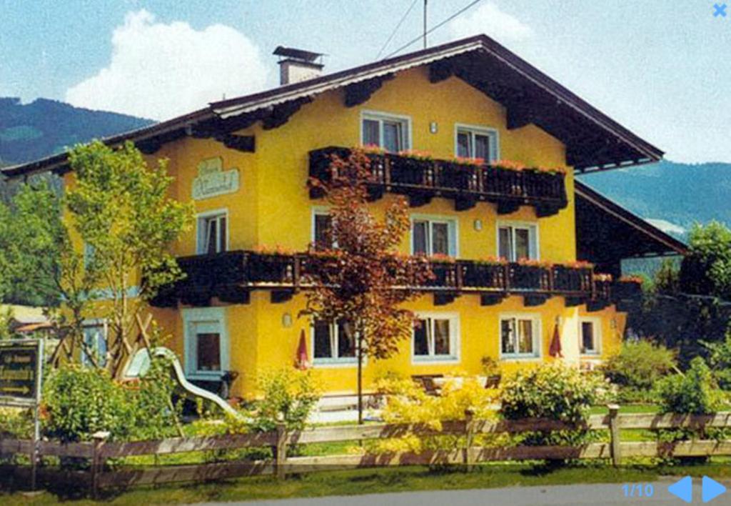 uma casa amarela com uma cerca em frente em Pension Klausnerhof em Brixen im Thale