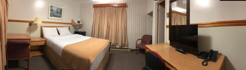 a hotel room with a bed and a flat screen tv at Kingsway Inn in Thunder Bay