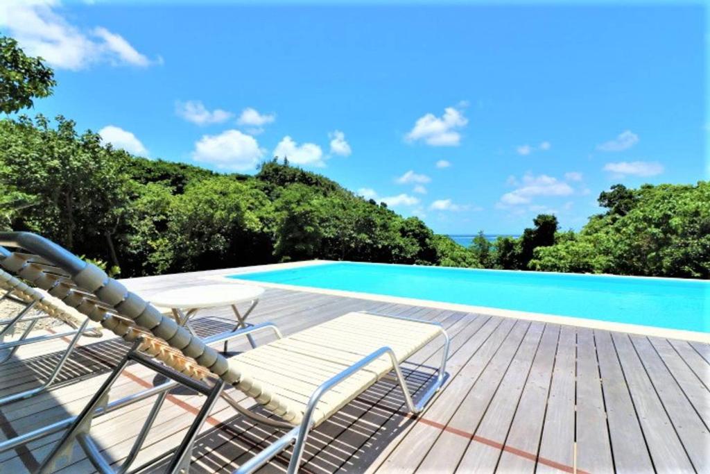 a deck with chairs and a swimming pool at Villa Del Mar Nosoko in Ishigaki Island