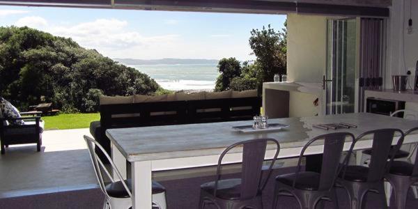 una mesa y sillas en una cocina con una gran ventana en Under Milkwood en Chintsa