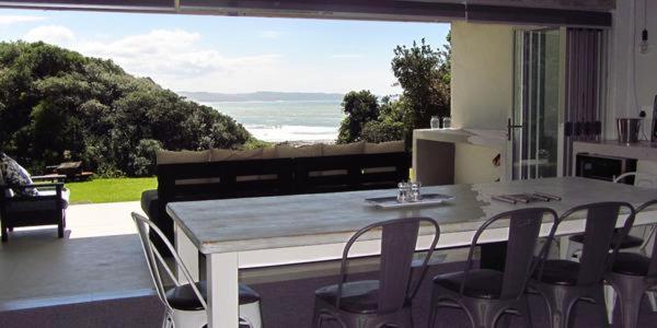 a table and chairs in a kitchen with a large window at Under Milkwood in Chintsa