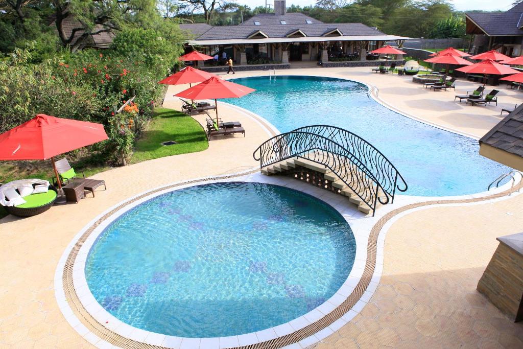 einen Blick über einen Pool mit roten Sonnenschirmen in der Unterkunft Enashipai Resort & Spa in Naivasha