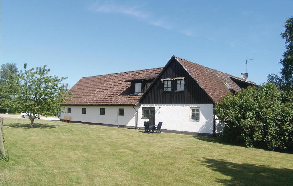 a white house with a black roof on a yard at Cozy Apartment In Saxtorp With Kitchenette in Saxtorp