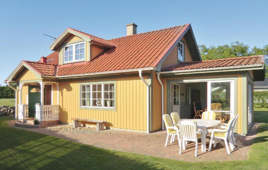 Awesome Home In Slvesborg With Kitchen في Falkvik: منزل أصفر مع طاولة وكراسي