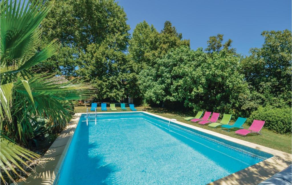 JonquièresにあるPet Friendly Home In Jonquires With Outdoor Swimming Poolのカラフルな椅子と木々が備わるスイミングプール