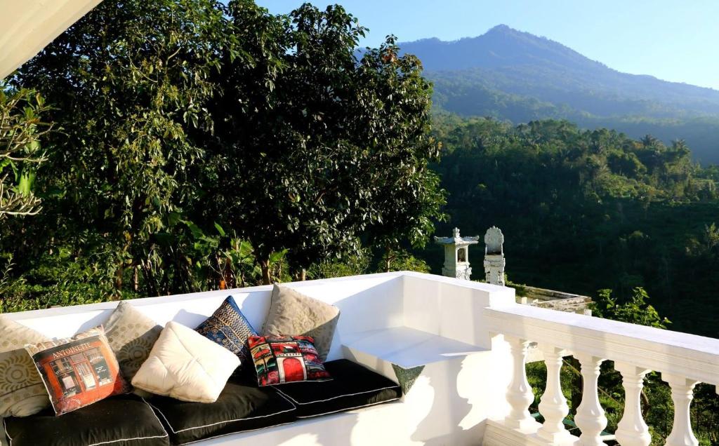 un sofá en un balcón con vistas a la montaña en Pondok Plantation Luxury Mountain Escape Bedugul, en Bedugul