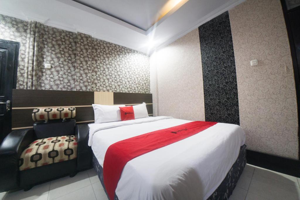 una camera d'albergo con un grande letto e una sedia di RedDoorz Syariah near RSUD Ainun Habibie Gorontalo a Limboto