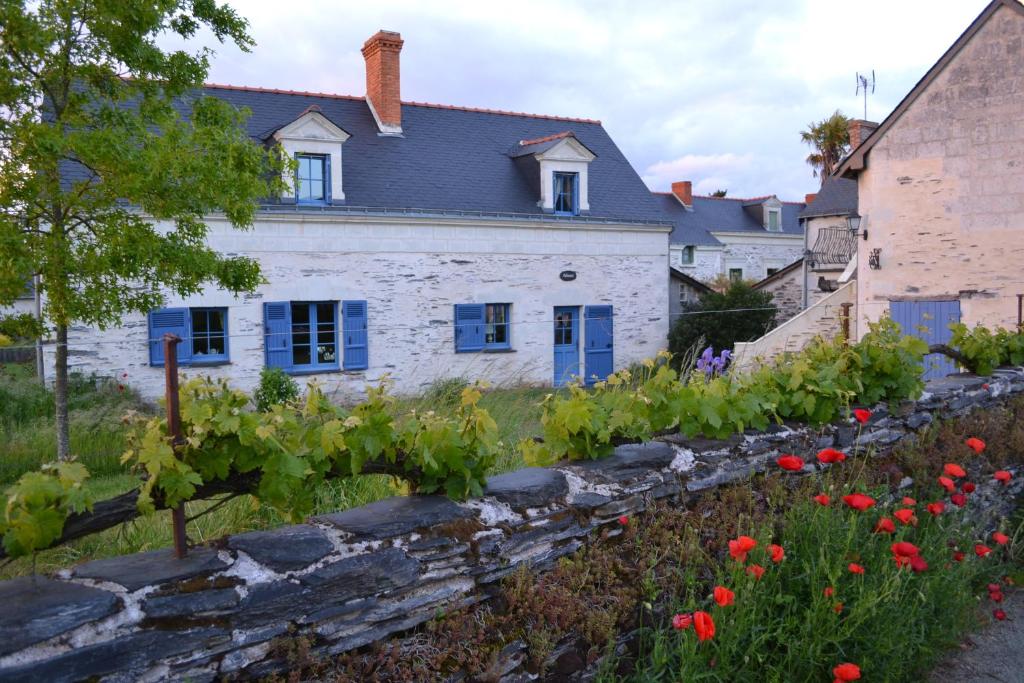 una casa con un jardín con flores rojas en Gîte Dagueloire en La Daguenière