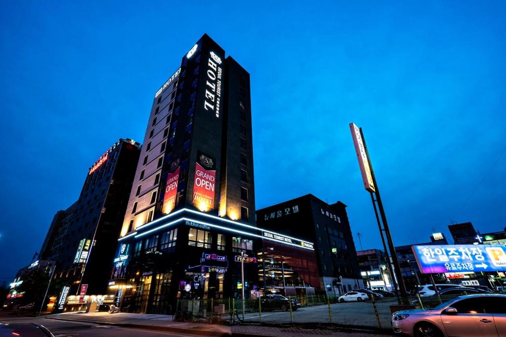 Siheung Seoul Tourist Hotel في Siheung: مبنى طويل به لافتات نيون على جانبه