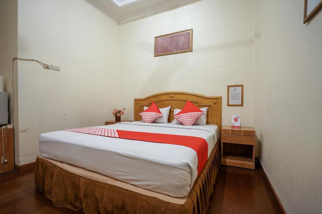 1 dormitorio con 1 cama grande con almohadas rojas y blancas en SUPER OYO 1173 Hotel Shofa Marwah en Palembang