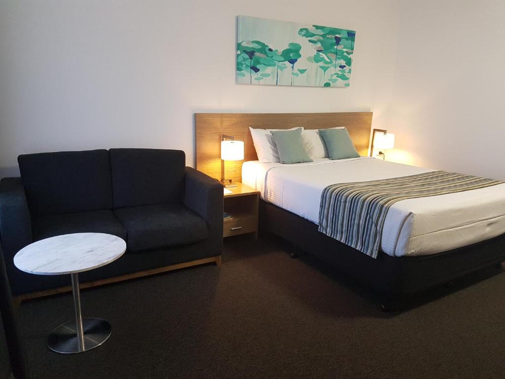 una camera d'albergo con letto e sedia di Mid City Motor Inn Singleton a Singleton