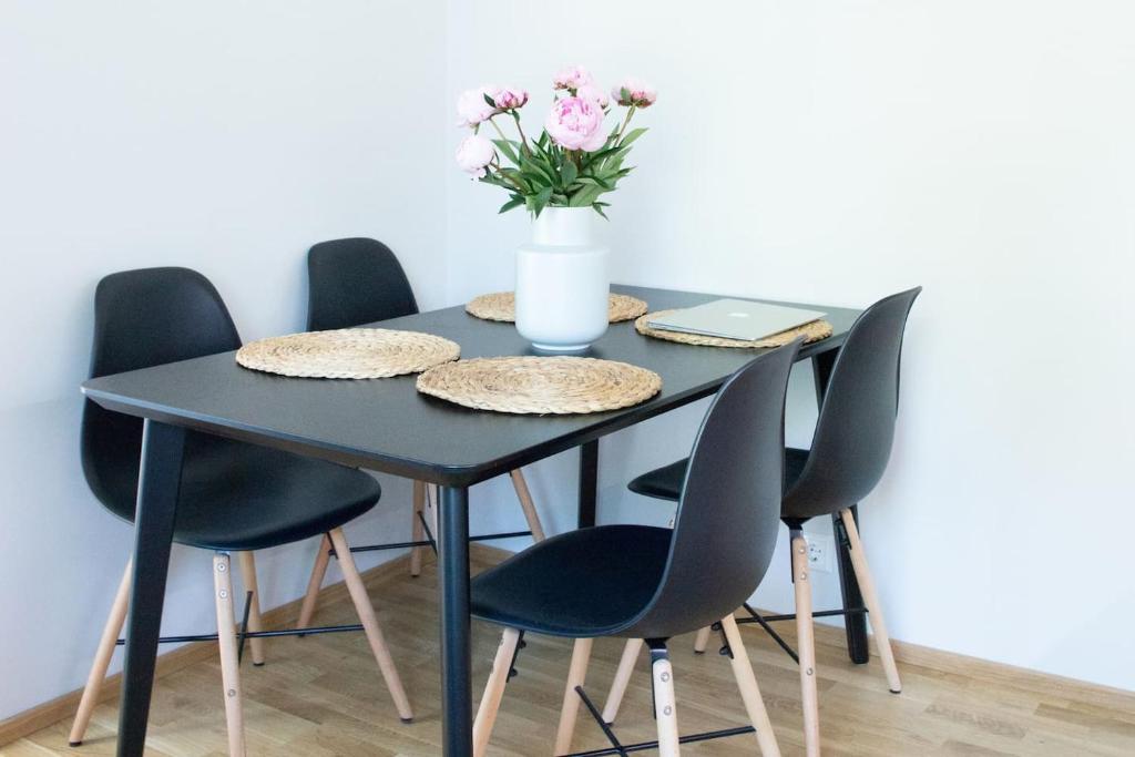 una mesa negra con sillas y un jarrón de flores en Modern apartment in the heart of Kärdla, en Kärdla