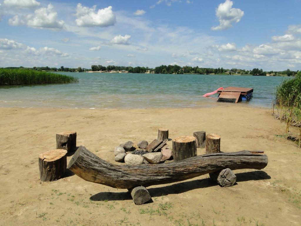 a wooden boat sitting on a beach next to the water at Lary Camping Homes - Domki Gorzewo in Gostynin