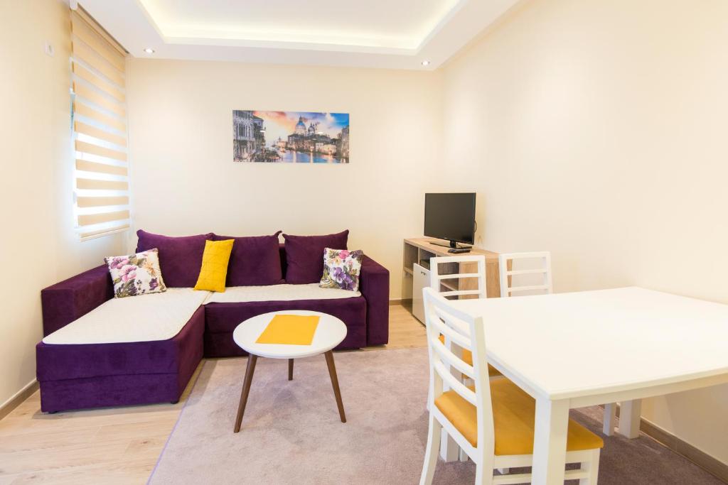 ein Wohnzimmer mit einem lila Sofa und einem Tisch in der Unterkunft Branka Apartments in Tivat