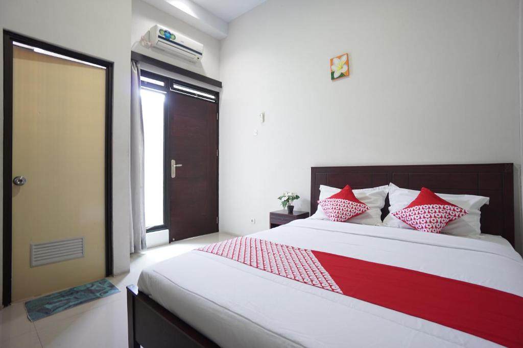 - une chambre dotée d'un grand lit avec des oreillers rouges et blancs dans l'établissement OYO 1236 Elite Residence, à Manado