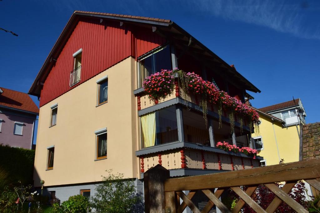 a building with a red roof and a balcony with flowers at Ferienwohnung Close in Lindenberg im Allgäu